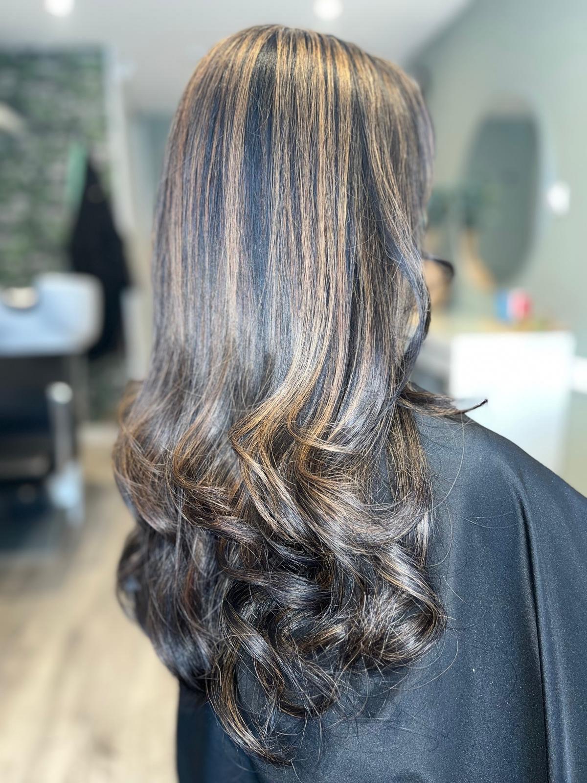Donker haar met lichte highlights en gekrulde punten, van achteren