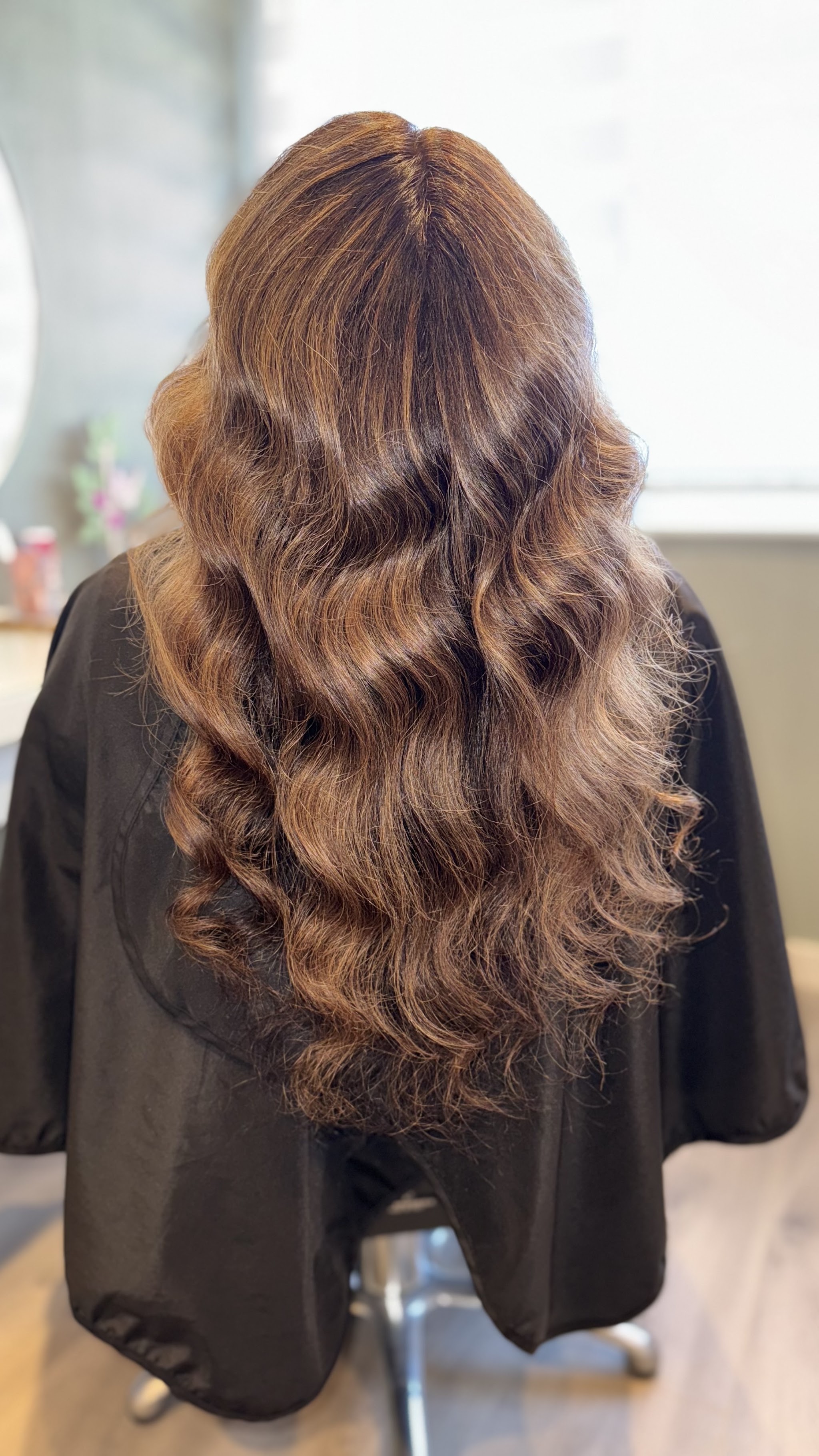 Lang bruin haar in grote krullen, van achteren in de salon