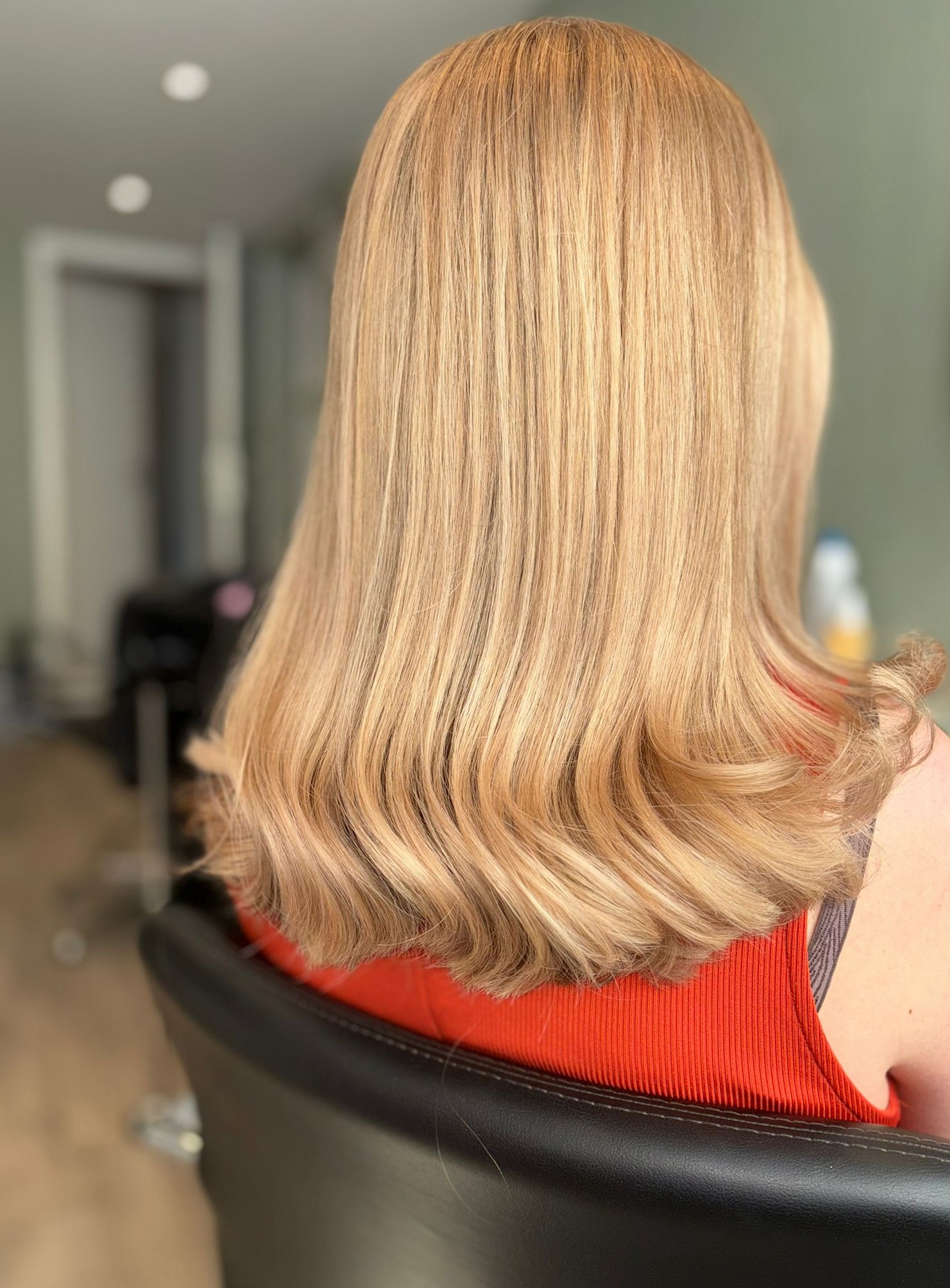 Goudblond, glad haar tot over de schouders, van achteren in de kappersstoel